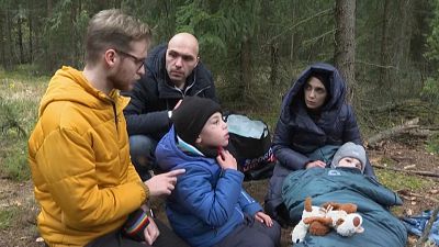 Un voluntario polaco habla con una familia de migrantes en un bosque cercano a la frontera con Bielorrusia