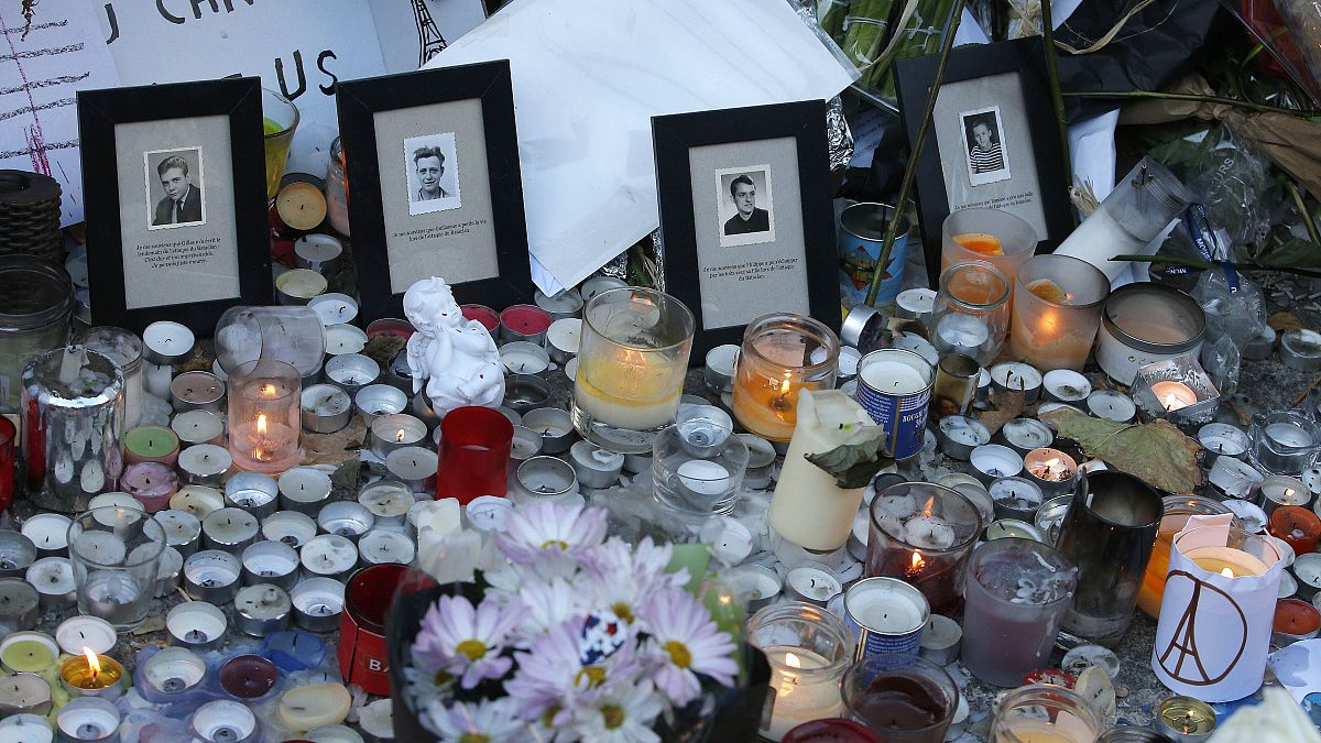 Pictures of victims are placed behind candles outside the Bataclan concert hall in Paris.