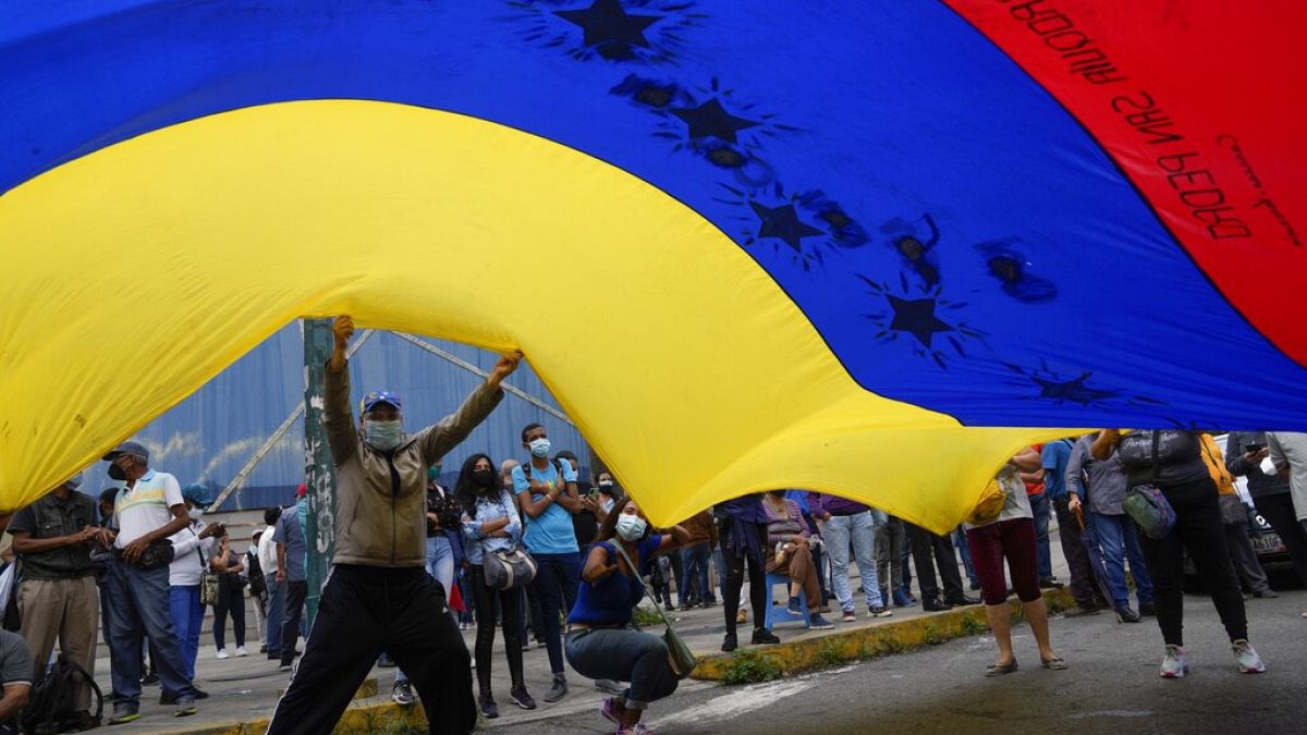 Simpatizantes del opositor Tomás Guanipa, candidato a la alcadía de Caracas, ondean una gigantesca bandera venezolana