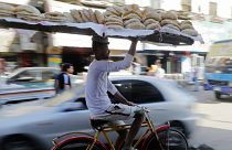 سائق دراجة هوائية يوازن صينية خبز في سوق السيدة زينب القاهرة ، مصر.