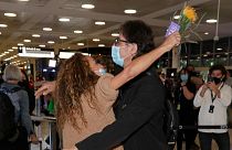 A woman is embraced by her brother after arriving on a flight from Los Angeles at Sydney Airport
