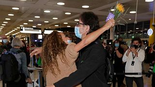A woman is embraced by her brother after arriving on a flight from Los Angeles at Sydney Airport