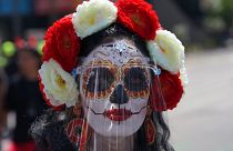 Una mujer disfrazada de "Catrina" y con una pantalla facial posa para una foto durante las festividades del Día de Muertos en la Ciudad de México, el 31 de octubre de 2021.
