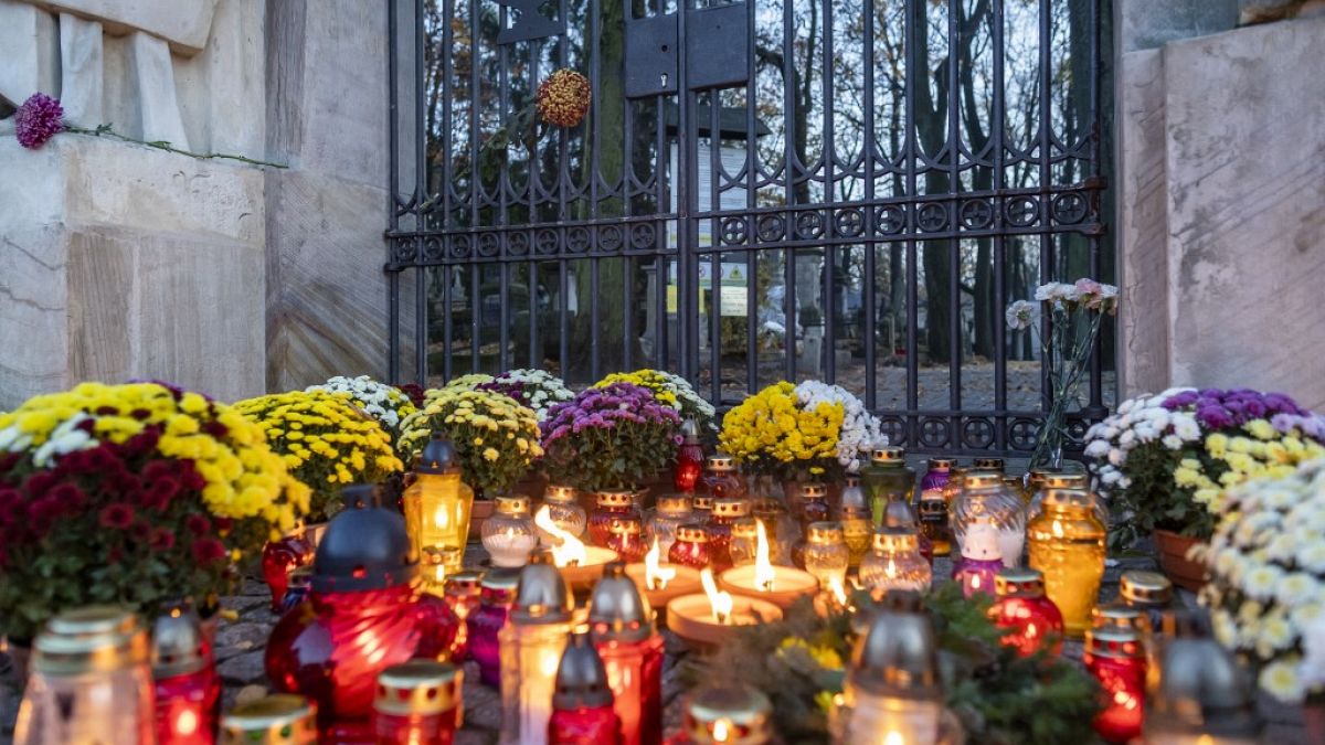 Candles and flowers lay in front of the locked gate to Powazki cementary in Warsaw, Poland, on November 1, 2020.