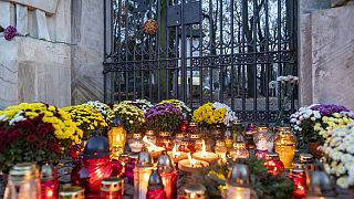 Candles and flowers lay in front of the locked gate to Powazki cementary in Warsaw, Poland, on November 1, 2020.