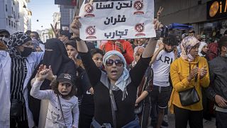 متظاهرة تحمل لافتة كتب عليها "نحن لسنا فشران تجارب" خلال مظاهرة رافضة لإلزامية جواز التلقيح، في العاصمة الرباط، المغرب، يوم الأحد 31 أكتوبر 2021