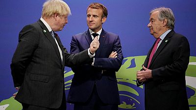 Britain's PM Boris Johnson (L) and UN Secretary General Antonio Guterres (R) greet French President Emmanuel Macron (C) as he arrives to attend the COP26 in Glasgow.