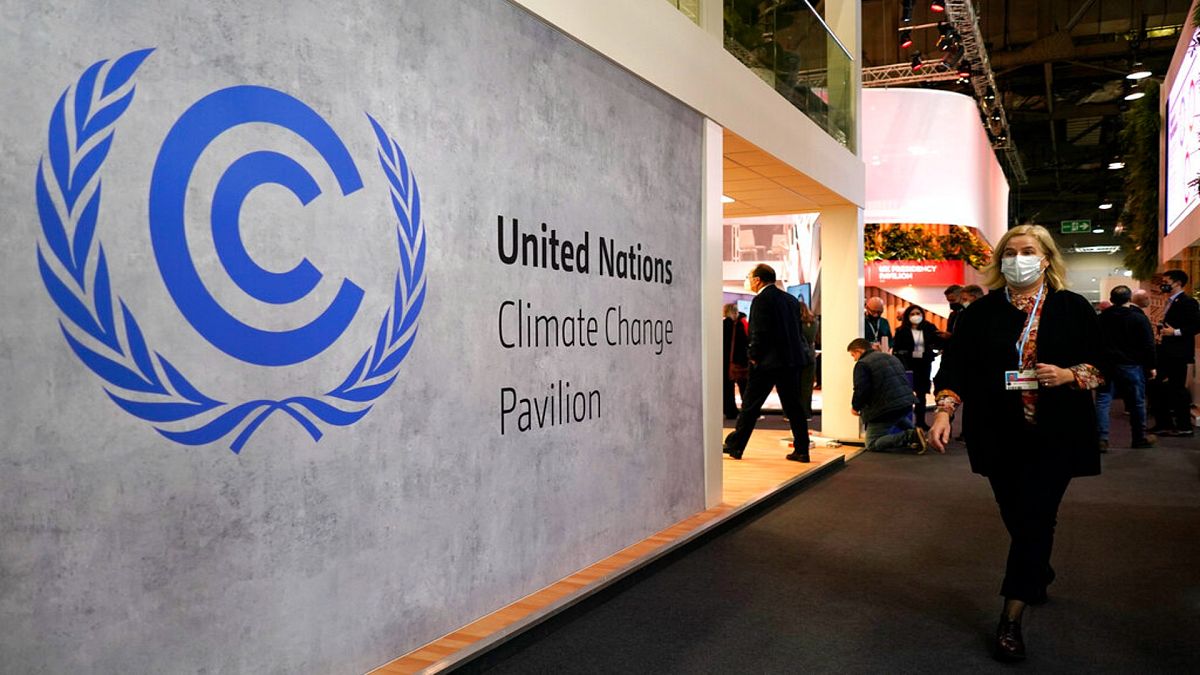 A woman walks by a sign inside the COP26 UN Climate Summit in Glasgow, Scotland, Tuesday, Nov. 2, 2021. 