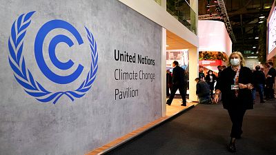 A woman walks by a sign inside the COP26 UN Climate Summit in Glasgow, Scotland, Tuesday, Nov. 2, 2021.