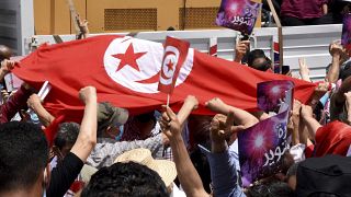 متظاهرون يرفعون العلم التونسي خلال احتجاج في تونس العاصمة ضد حكومة المشيشي والبرلمان، السبت 5 حزيران/يونيو 2021.