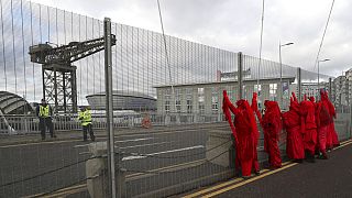 Red Rebel Brigade climate protesters demonstrate by the security fencing outside the Scottish Event Campus, the venue for the COP26 U.N. Climate Summit in Glasgow, on Tuesday