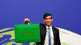 Britain's Chancellor of the Exchequer Rishi Sunak holds up a Green briefcase as he arrives for a speech at the COP26 U.N. Climate Summit in Glasgow, Nov. 3, 2021. 