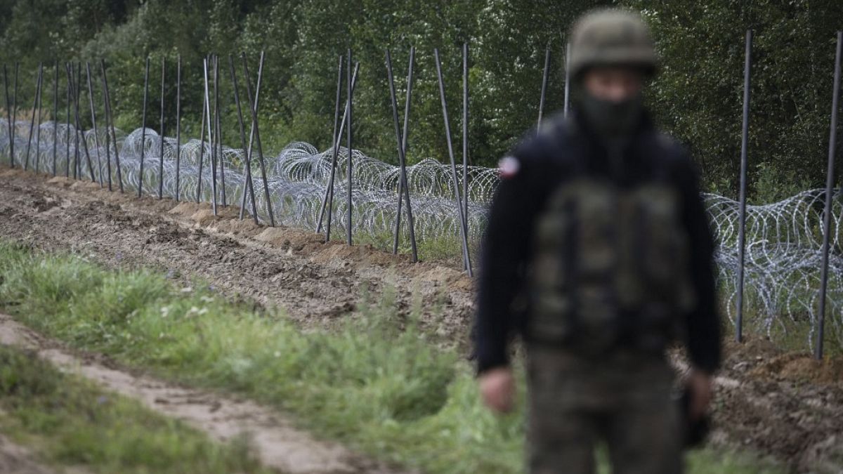 A Polish soldier walks past a barbed wire fence on the border with Belarus in Zubrzyca Wielka.