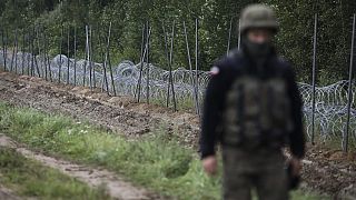 A Polish soldier walks past a barbed wire fence on the border with Belarus in Zubrzyca Wielka.