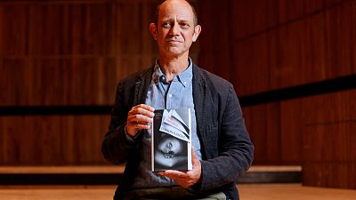 South African author Damon Galgut poses with his book 'The Promise' shortlisted for the 2021 Booker Prize for Fiction  in London on October 31, 2021.