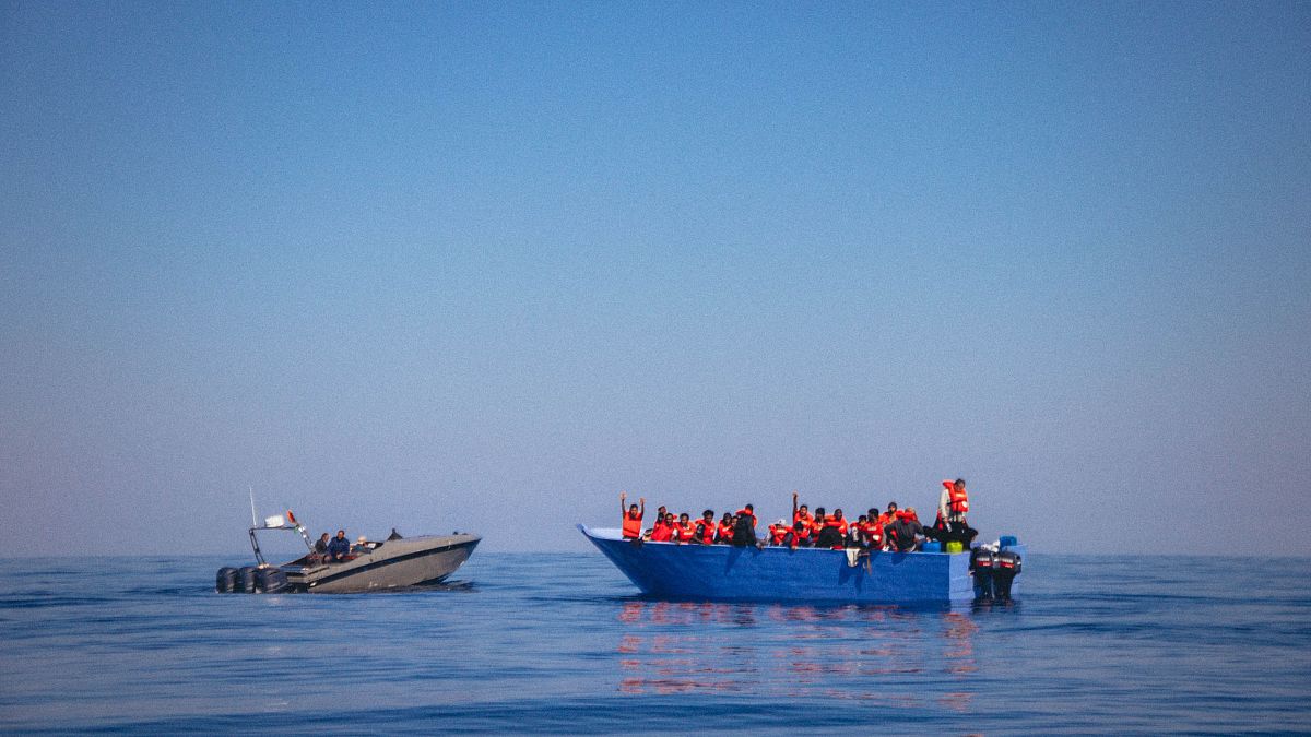 Лодка с мигрантами, подавшими сигнал бедствия, и катер береговой охраны Ливии. Вид с борта спасательного судна Sea-Eye