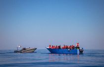 Лодка с мигрантами, подавшими сигнал бедствия, и катер береговой охраны Ливии. Вид с борта спасательного судна Sea-Eye