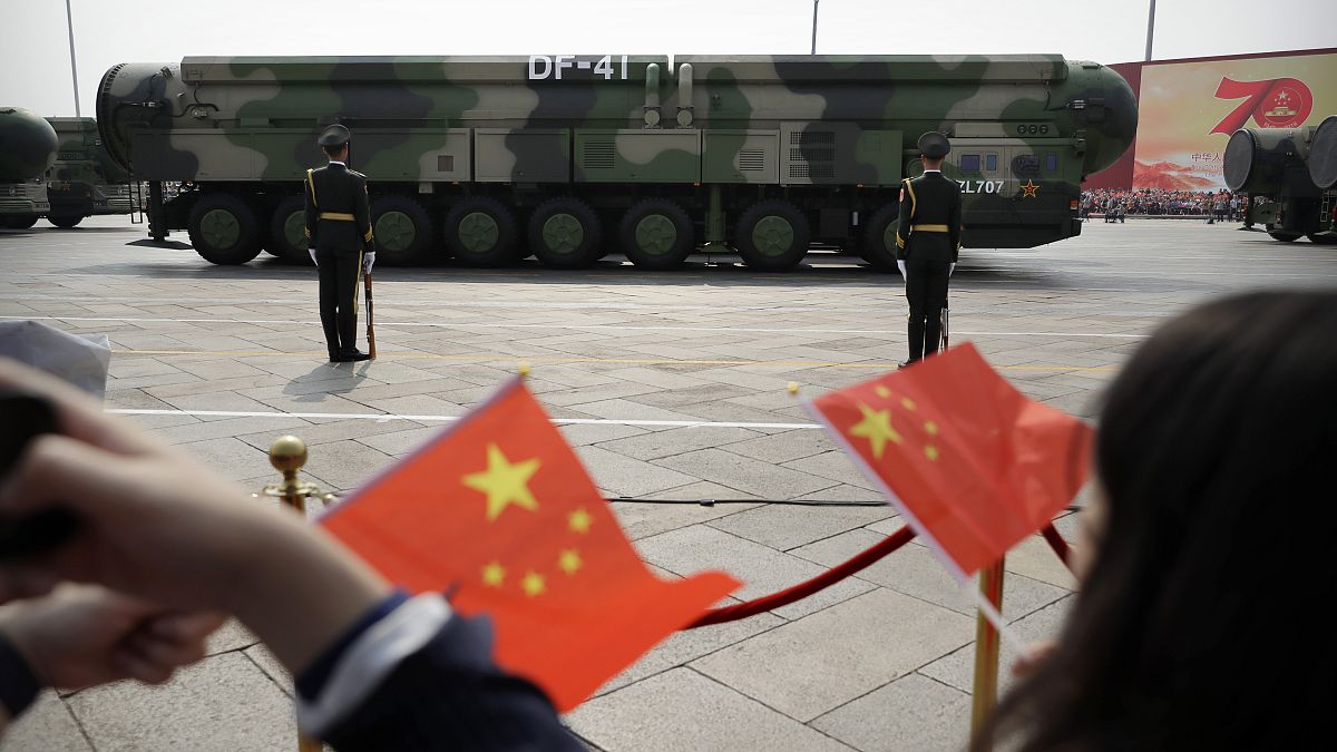 Spectators wave Chinese flags as military vehicles carrying DF-41 ballistic missiles roll during a parade in Beijing, Oct. 1, 2019.