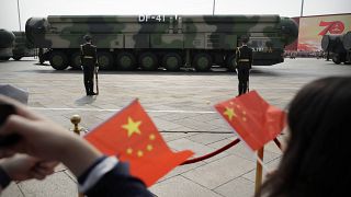 Spectators wave Chinese flags as military vehicles carrying DF-41 ballistic missiles roll during a parade in Beijing, Oct. 1, 2019.