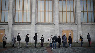 People line up for vaccination injections in front of at the vaccination center of the Malteser relief service on the fair grounds in Berlin, Germany, Wednesday, Nov. 3, 2021