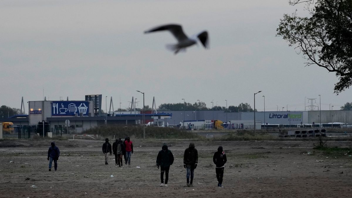 Migrants walk near a camp in Calais, northern France, Thursday, Oct. 14, 2021. 