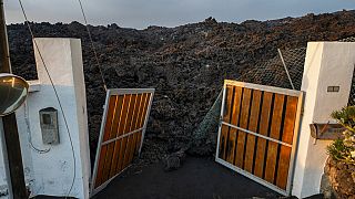 Imagen del portón de una vivienda invadido por una colada de lava del volcán de Cumbre Vieja, en la isla de La Palma