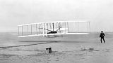 أورفيل رايت، مستلقياً على أدوات التحكم في الجناح السفلي، يقود طائرة رايت فلاير في أول رحلة تعمل بالطاقة بواسطة طائرة أثقل من الهواء، 17 كانون الأول / ديسمبر 1903
