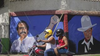 A motorcyclist rides past a mural of Nicaraguan President Daniel Ortega, left, and revolutionary hero Cesar Augusto Sandino during general elections in Managua, Nicaragua.