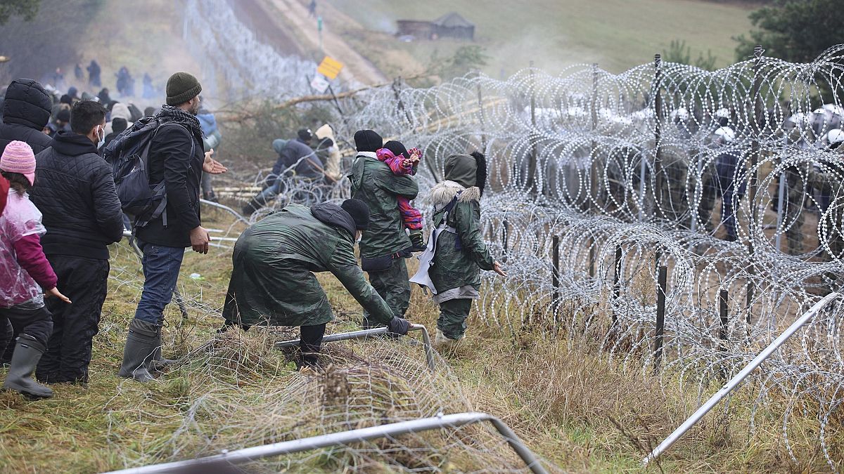 Migrants from the Middle East and elsewhere break down the fence as they gather at the Belarus-Poland border near Grodno, Belarus, Monday, Nov. 8, 2021.
