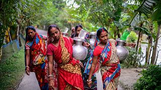 Women walk homewards carrying drinking water in Bonbibi Tala in Satkhira, Bangladesh. Each woman walks up to four kilometres daily.