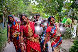 Women walk homewards carrying drinking water in Bonbibi Tala in Satkhira, Bangladesh. Each woman walks up to four kilometres daily.