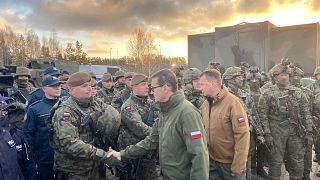Poland's Prime Minister Mateusz Morawiecki (C) and Defence Minister Mariusz Blaszczak (R) meet border guards and troops at Kuznica, Poland-Belarus border, Nov. 9, 2021.