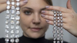 A Christie's employee holds up a pair of diamond bracelets once owned by Marie Antoinette of France, in silver and yellow gold, circa 1776, during a preview at the Christie's,