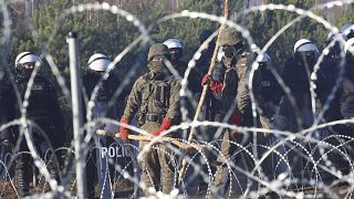 الشرطة البولندية وحرس الحدود يقفون بالقرب من الأسلاك الشائكة حيث يتجمع مهاجرون من الشرق الأوسط وشمال أفريقيا عند الحدود بين بيلاروس وبولندا