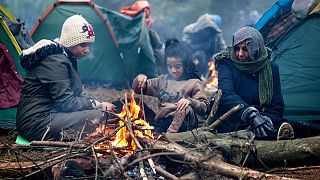 Migrants from the Middle East and elsewhere warmup at the fire gathering at the Belarus-Poland border near Grodno, Belarus, Wednesday, Nov. 10, 2021.