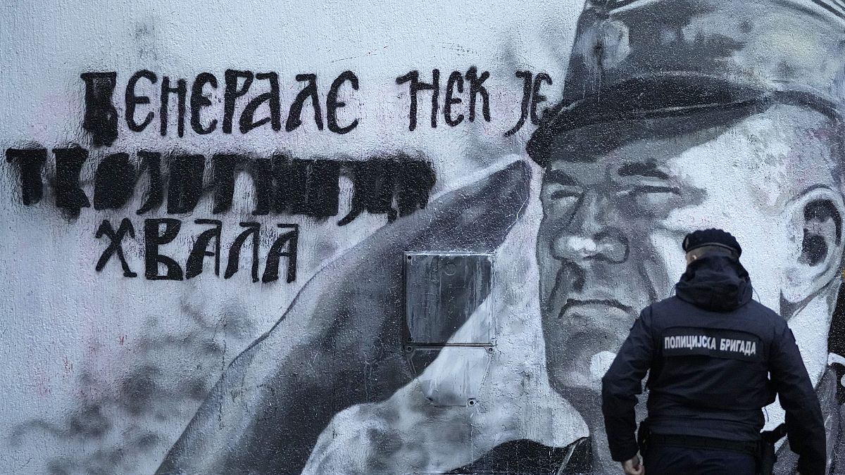 A police officer walks by a mural of former Bosnian Serb military chief Ratko Mladic in Belgrade, Serbia, Tuesday, Nov. 9, 2021.