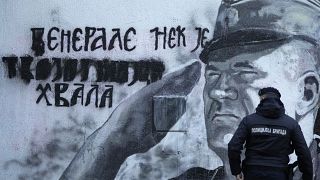 A police officer walks by a mural of former Bosnian Serb military chief Ratko Mladic in Belgrade, Serbia, Tuesday, Nov. 9, 2021.