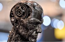 مجسم لرأس إنسان معدني مصنوع من أجزاء المحرك يرمز إلى الذكاء الاصطناعي "AI" في معرض "إيسن موتور شو"  في مدينة إيسن بألمانيا، 29 نوفمبر 2019