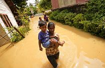 Une femme porte un enfant dans une rue inondée de Kochchikade, à 30 km de Colombo, Sri Lanka, le 10 novembre 2021