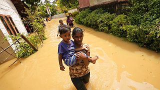 Une femme porte un enfant dans une rue inondée de Kochchikade, à 30 km de Colombo, Sri Lanka, le 10 novembre 2021