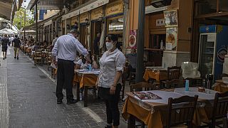 Εργαζόμενοι αναμένουν να υποδεχθούν πελάτες στο Μοναστηράκι στο κέντρο της Αθήνας
