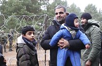 Un homme, un migrant, tenant dans ses bras un bébé, debout aux côtés d'un autre enfant dans le froid, à la frontière entre le Bélarus et la Pologne, 10 novembre 2021