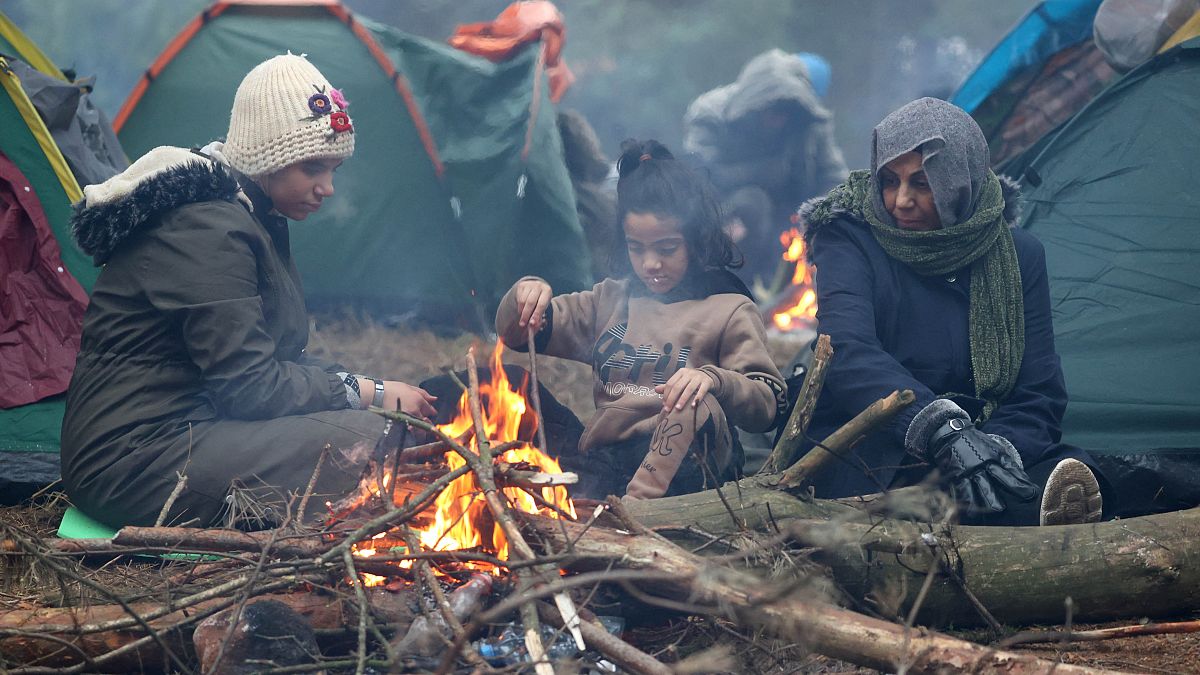 Menschen an der belarussisch-polnischen Grenze wärmen sich an einem Feuer