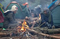 Menschen an der belarussisch-polnischen Grenze wärmen sich an einem Feuer