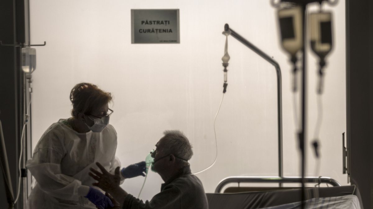 A member of the medical staff comforts a COVID-19 positive patient at the University Emergency Hospital waiting area, in Bucharest, Romania, Monday, Nov. 8, 2021.