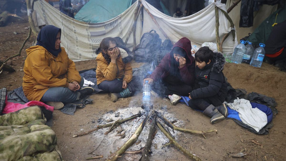 Des femmes et des enfants se réchauffant autour d'un feu à la frontière entre le Bélarus et la Pologne près de Grodno, Bélarus, 11 novembre 2021