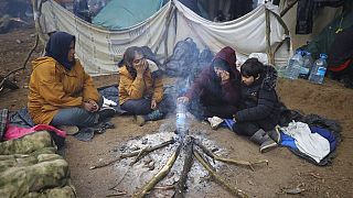 Des femmes et des enfants se réchauffant autour d'un feu à la frontière entre le Bélarus et la Pologne près de Grodno, Bélarus, 11 novembre 2021