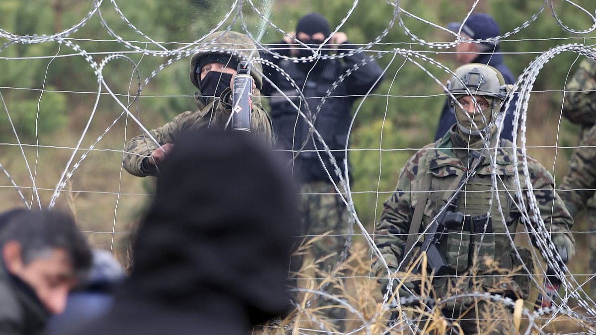 Des gardes-frontières polonais se tiennent près des barbelés alors que des migrants se rassemblent à la frontière entre la Biélorussie et la Pologne (novembre 2021).