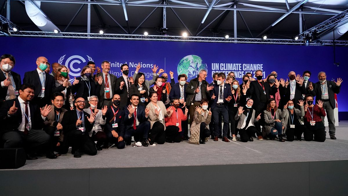 Delegates from different countries pose for a group photograph together on stage in the plenary room at the COP26 UN Climate Summit, in Glasgow, Scotland, Nov. 13, 2021.