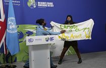 Podium in Glasgow gestürmt. Auf dem Plakat steht: "Das Klima ändert sich. Warum andern wir uns nicht?"
